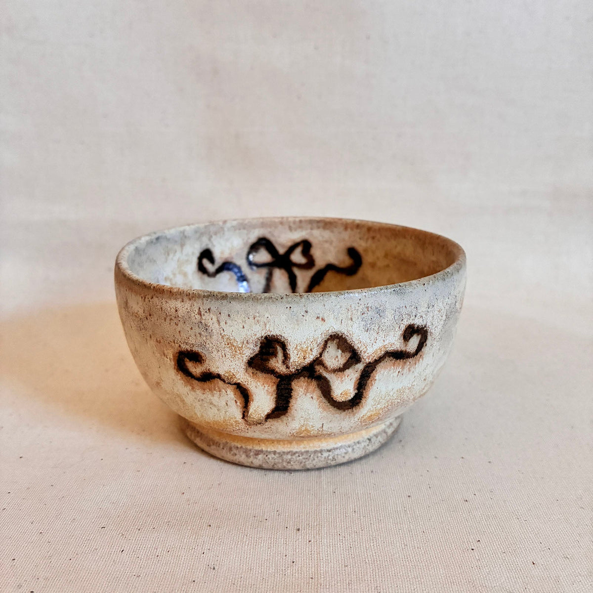Footed cream-glazed coupe bowl with brown ribbon decoration