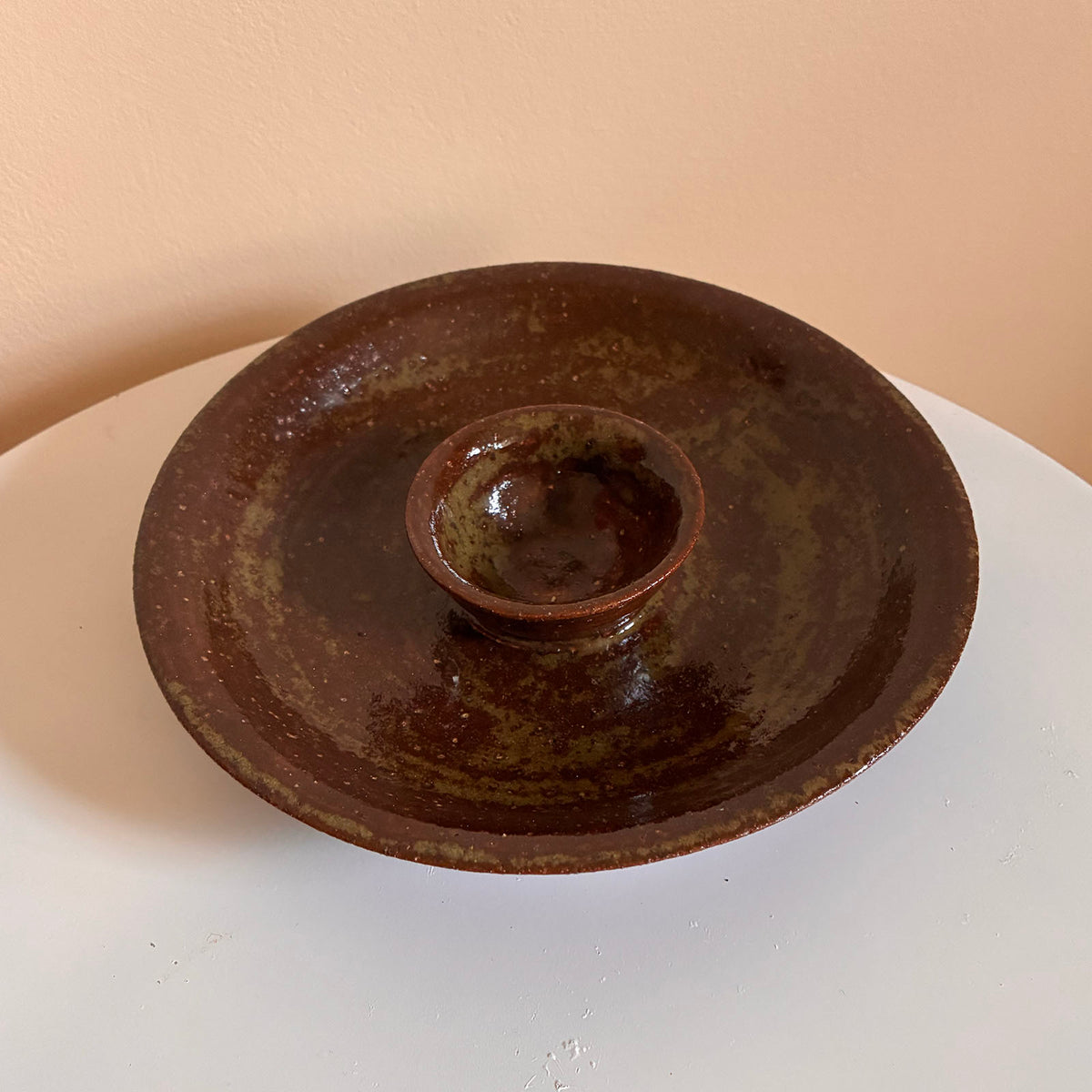 Wide olive-brown lava-fleck dish with a small central footed cup for dip