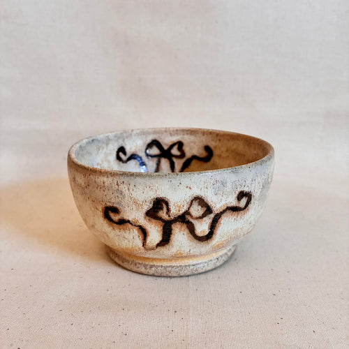 Footed cream-glazed coupe bowl with brown ribbon decoration