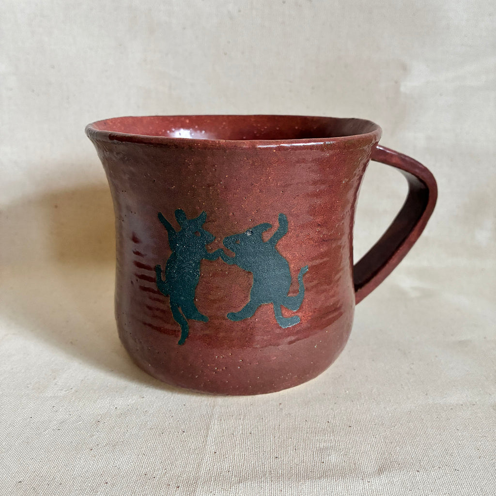 Reddish-brown mug with dancing rat and deer motifs