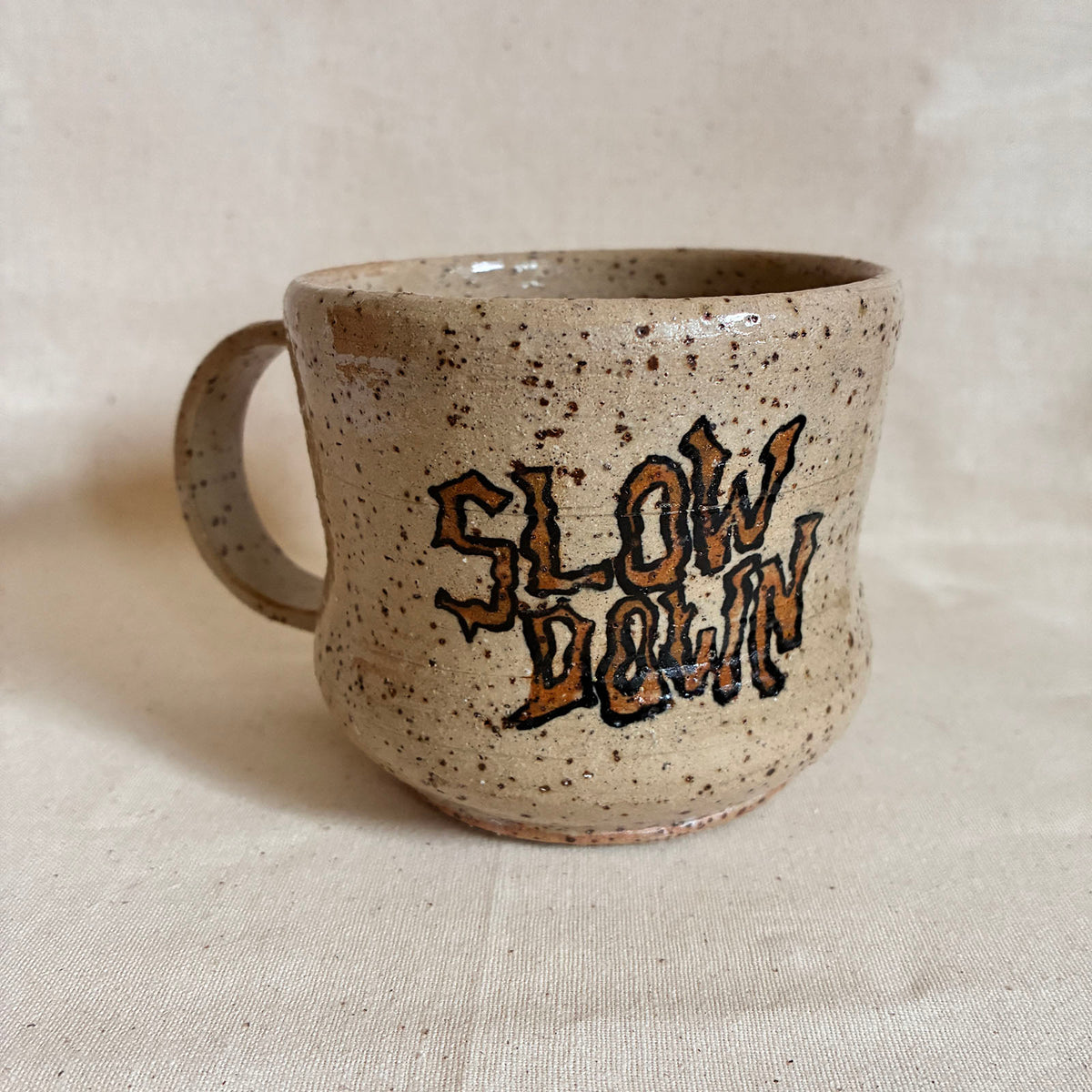 Speckled cream mug with hand-lettered Slow Down artwork