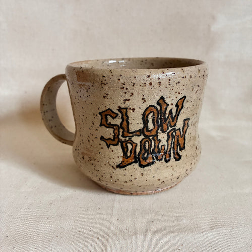 Speckled cream mug with hand-lettered Slow Down artwork